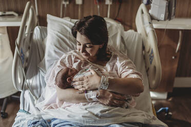 Mid view of mother in hospital bed looking at newborn son - CAVF77674