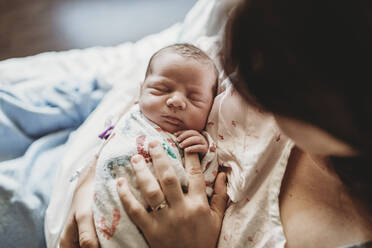 Draufsicht auf die Mutter, die die Finger des neugeborenen Jungen im Krankenhausbett hält - CAVF77675