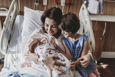 Mid view of mother holding newborn son meeting siblings - CAVF77688