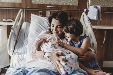 Mid view of mother holding newborn son meeting siblings - CAVF77691