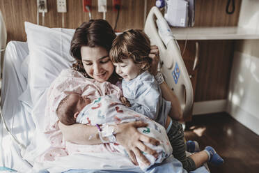 Mid view of mother holding newborn son meeting siblings - CAVF77692