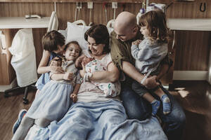 Mittelansicht der ganzen Familie mit ihrem neugeborenen Sohn im Krankenhaus - CAVF77694