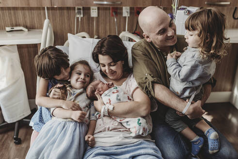 Mittelansicht der ganzen Familie mit ihrem neugeborenen Sohn im Krankenhaus - CAVF77696