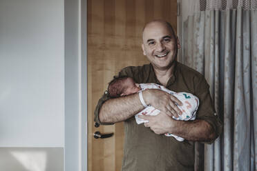 Vater hält neugeborenen Jungen in Decken eingewickelt im Krankenhaus - CAVF77705