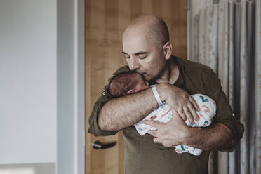 Glücklicher Vater küsst neugeborenen Sohn in Decken eingewickelt im Krankenhaus - CAVF77707