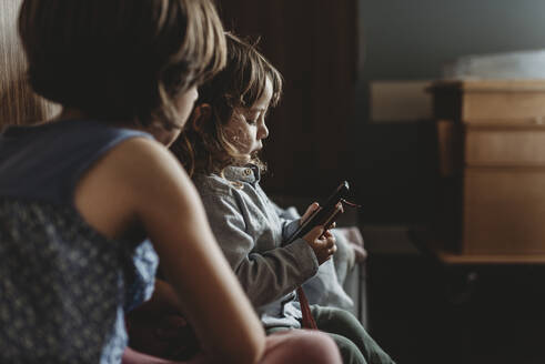 Seitenansicht eines Jungen, der im Krankenhaus am Telefon spielt - CAVF77716