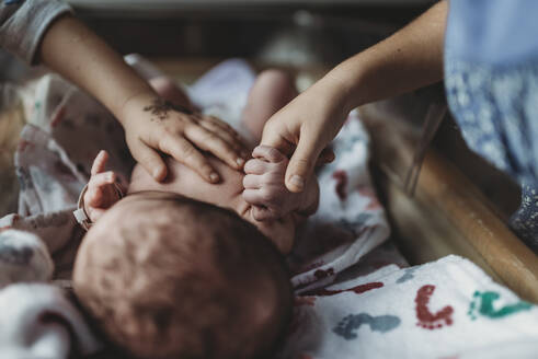 Detail of siblings holding newborn baby brother's hand in hospital - CAVF77723