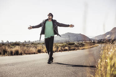 Man with outstretched arms walking on country road - SDAHF00671