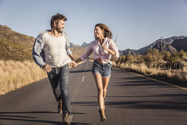 Happy couple running on a country road - SDAHF00696