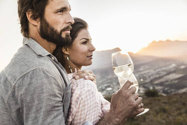 Verliebtes Paar bei einem Glas Weißwein auf dem Lande bei Sonnenuntergang - SDAHF00721
