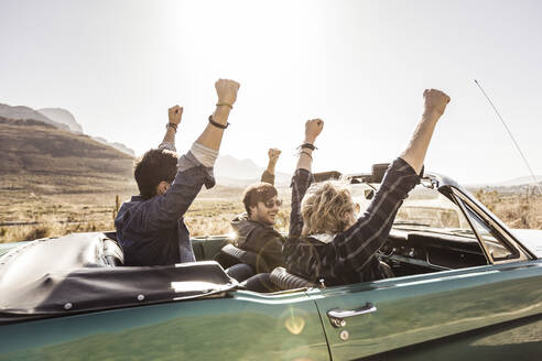 Happy friends in convertible car on a road trip - SDAHF00731