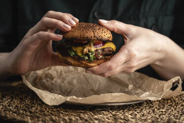 Russia, Hands of woman holding ready-to-eat hamburger with red bell pepper, onions and cheese - VPIF02178