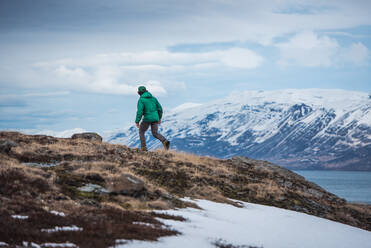 A man runs up a hill with mountains behind him in Iceland - CAVF77773