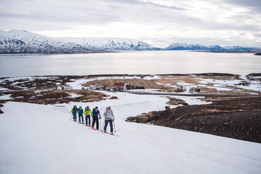 Eine Gruppe beim Skilanglauf in Island mit dem Meer im Hintergrund - CAVF77778