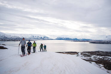 A group backcountry skiing in Iceland with the ocean in the background - CAVF77779
