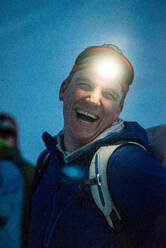 Ein Mann, der nachts mit einer Stirnlampe lacht - CAVF77809