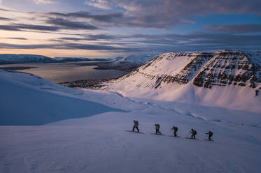 Gruppe von Menschen beim Sonnenaufgang in Island beim Skilanglauf - CAVF77821