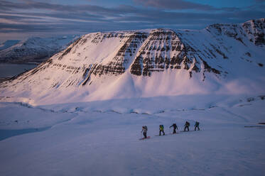Gruppe von Menschen beim Sonnenaufgang in Island beim Skilanglauf - CAVF77822