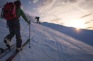 Two people backcountry skiing in Iceland at sunrise - CAVF77825