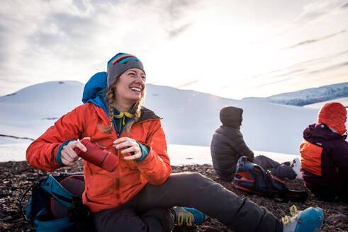 Frau lacht mit Kaffeemaschine, während draußen in Island Schnee liegt - CAVF77829