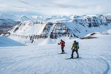 Man and woman skiing in Iceland with mountains in background - CAVF77837