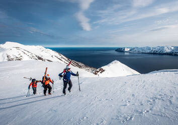 Männer wandern bergauf mit Himmel in Island mit Wasser im Hintergrund - CAVF77845