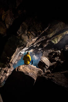 Frau sitzt vor einem Thermalbecken in einer Höhle - CAVF77862