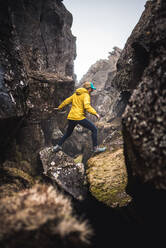 Woman in yellow jacket exploring thermal fissures in Iceland - CAVF77863