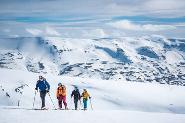 Eine Gruppe von Skifahrern beim Tourengehen in verschneiten Bergen in Island - CAVF77868