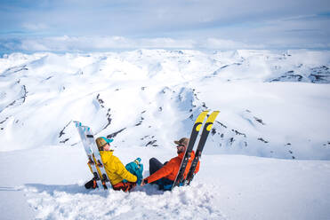 Ein Mann und eine Frau, die sich mit Skiern vor einer Bergkulisse entspannen - CAVF77869