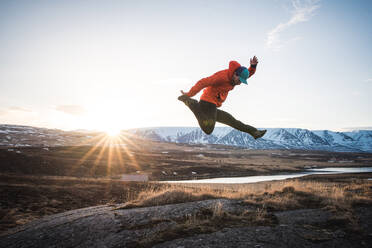 Man jumping with mountains and sun in background - CAVF77880