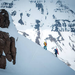 A woman and a man hike up a mountain ridge in Iceland - CAVF77888