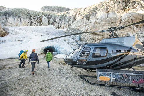 Ein Bergführer nähert sich mit seinen Gästen einer Gletschereishöhle. - CAVF77902