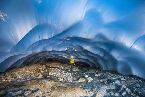 Bergsteiger steht in einer Gletscherhöhle. - CAVF77907