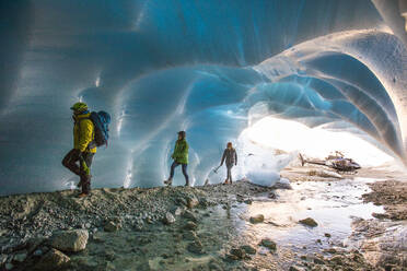 Adventure guide brings two female clients into a glacial cave. - CAVF77908