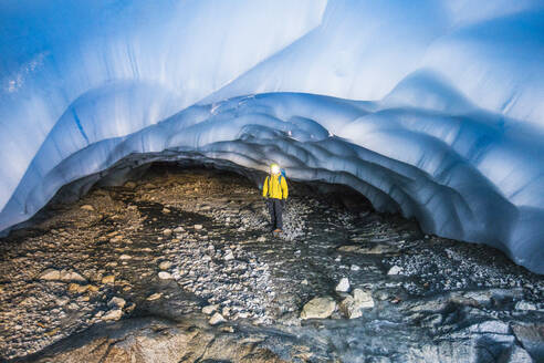 Forscher steht in einer Höhle unter einem Gletscher. - CAVF77910