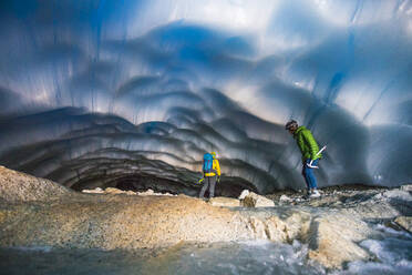 Rear view of couple exploring an ice cave. - CAVF77913