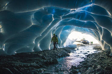 Ice climber enters ice cave to find a climbing route. - CAVF77920