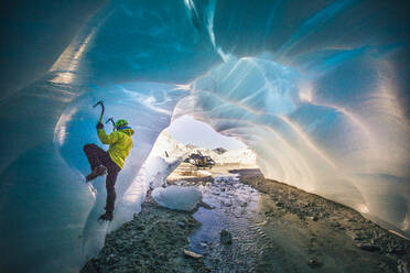 Man ice climbing in cave during luxury adventure tour. - CAVF77925