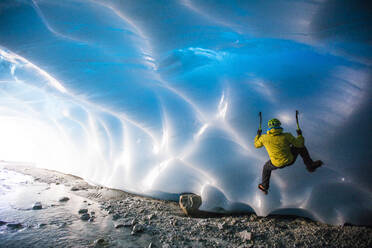 Man ice climbing on glacial ice in ice cave. - CAVF77928