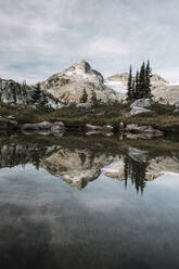 Alpine mountain scene reflecting in calm tarn - CAVF77938