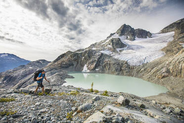 Backpacker hiking with view of lake and mountains - CAVF77954