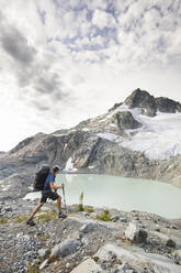 Backpacker hiking with view of lake and mountains - CAVF77955