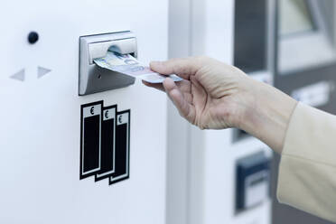 Frauenhand, die eine Banknote in einen Geldautomaten steckt - FLLF00438
