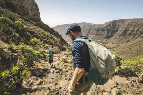 Father and little son with backpacks walking on a hiking trail in the mountains, La Gomera, Canary Islands, Spain stock photo