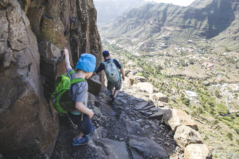 Rückenansicht von Vater und kleinem Sohn mit Rucksäcken auf einem Wanderweg in den Bergen, La Gomera, Kanarische Inseln, Spanien, lizenzfreies Stockfoto