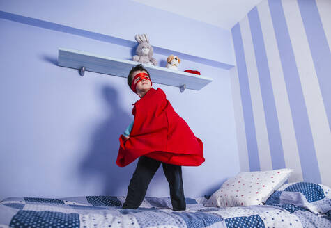 Kleiner Junge spielt Superheld, stehend auf seinem Bett - LJF01479