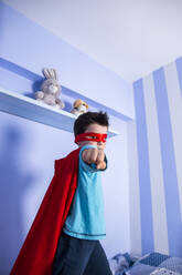 Little boy playing super hero, standing on his bed - LJF01480