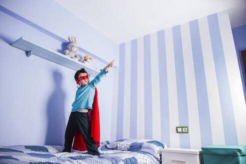 Little boy playing super hero, standing on his bed - LJF01481