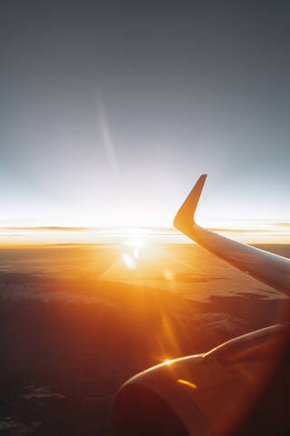 Finland, Wing of airplane flying against rising sun stock photo